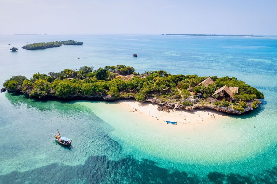 Zanzibar's beaches offer a picture-perfect setting for a summer vacation, as seen from an aerial view, with palm trees, umbrellas, white sand, and the crystal-clear waters of the Indian Ocean.